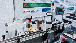 Automatic equipment for self-adhesive labels on round plastic bottles