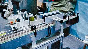 Automatic labeling machine for sticking self-adhesive labels on glass bottles