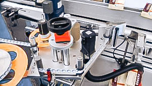 Automatic equipment for sticking self-adhesive labels on cardboard boxes of pharmaceutical production